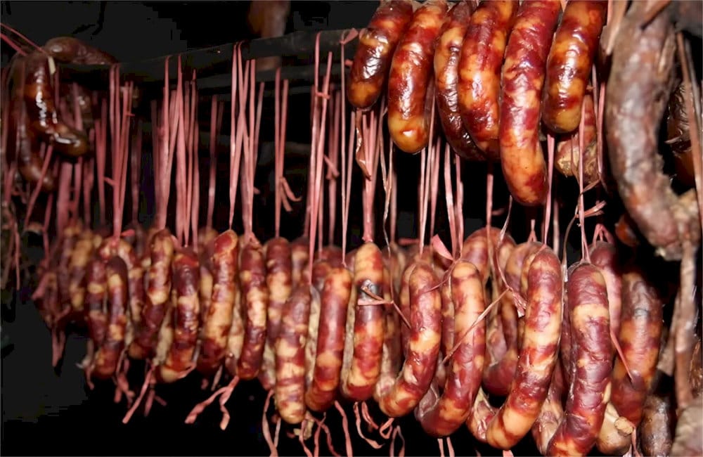 Sausages hanging in rows above a kitchen fire, slow-cured for depth of flavor 